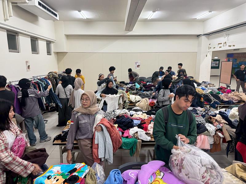 會場擺滿多樣衣物，同學們細心比較尺寸與款式。透過捐衣與分享，讓物資再生、減少浪費。