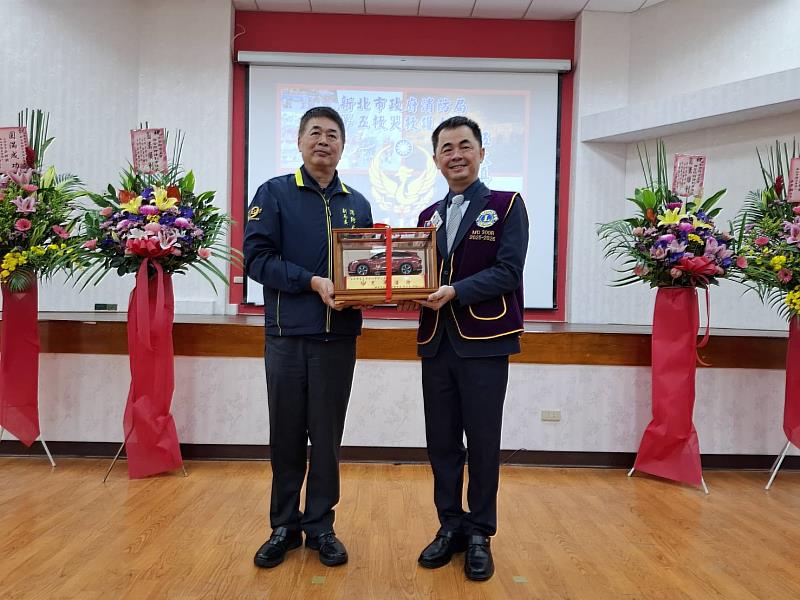 消防局回贈消防災勘車模型。（左1：消防局副局長蔡武忠，右1：家登精密工業股份有限公司董事長邱銘乾）