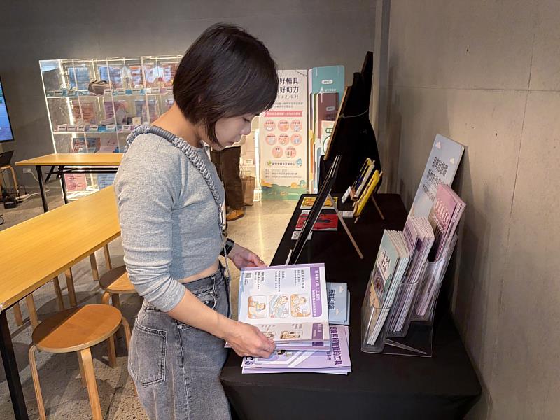 114年國際身障日系列活動展示易讀文件及育兒輔具，民眾翻閱手冊內容。
