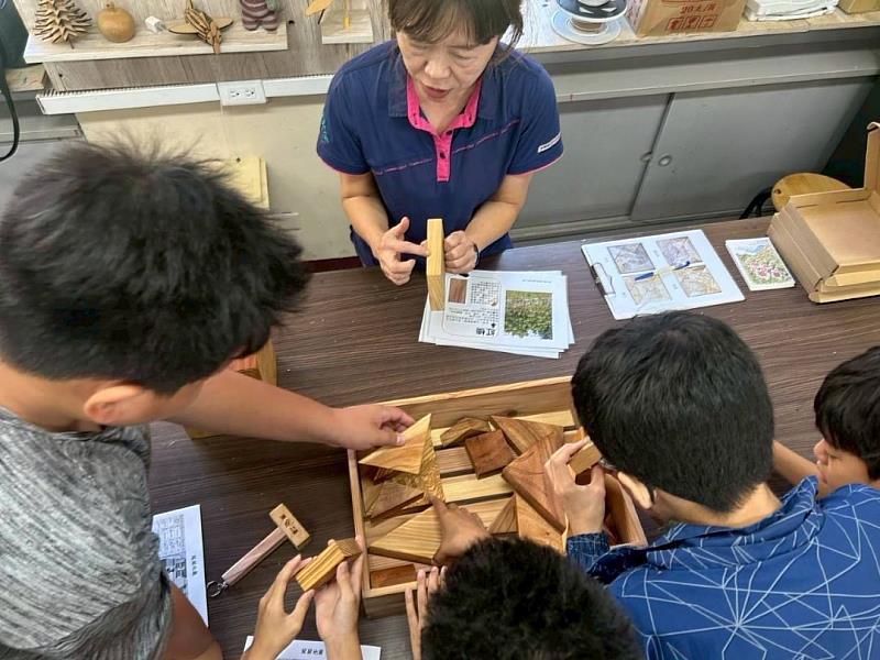 由知本自然教育中心講師帶領學童觀察國產材教具，介紹不同樹種的木紋特色。
