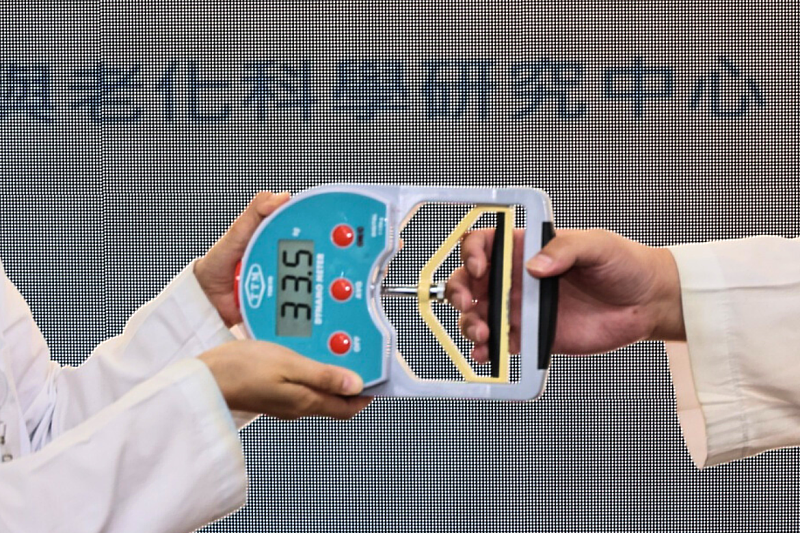 A clinician conducts a handgrip strength test, one of the key indicators used to assess muscle function in the updated Asian sarcopenia guidelines.