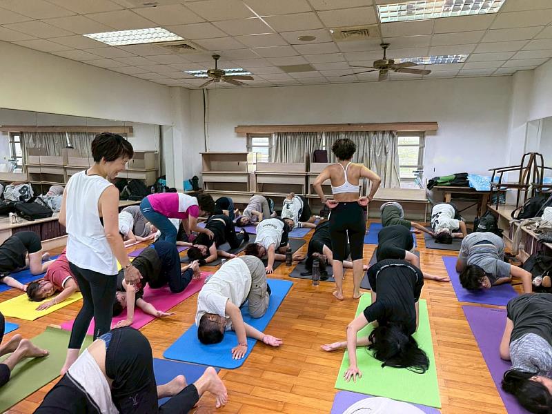 南華大學以自然瑜珈課程引領身心平衡，羅涼萍老師與兩位日本瑜珈老師調整學生姿勢。