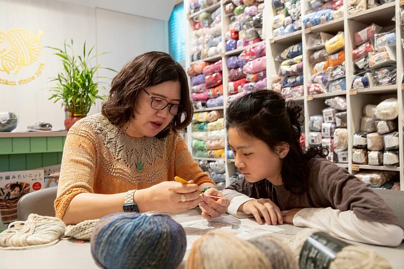 「新弘觀毛線行」主理人張玉鈴（左）指導學生判讀織圖，並親自示範編織。