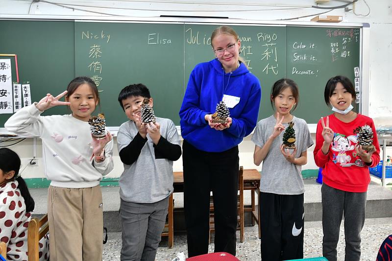 西門國小學伴與大學伴展示共同完成的松果彩繪作品，跨國情誼在歡樂中定格。