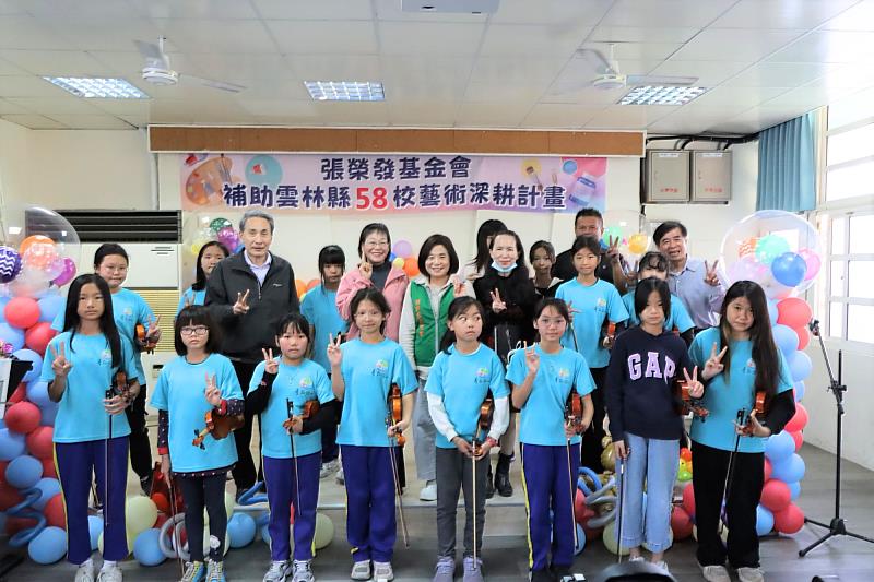 臺西國小小朋友展現小提琴學習成果，執行長鍾德美（中著綠背心）、雲林縣副縣長謝淑亞（第二排左三）、雲林縣政府教育處處長邱孝文（第二排左二）、臺西國小校長蔡維哲（第三排右一）與學童一同合影。