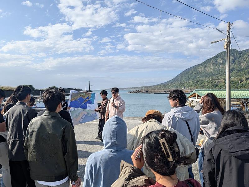 臺東大學公事系林嘉男老師利用國土功能分區圖在金樽漁港向學生說明該區的爭議。