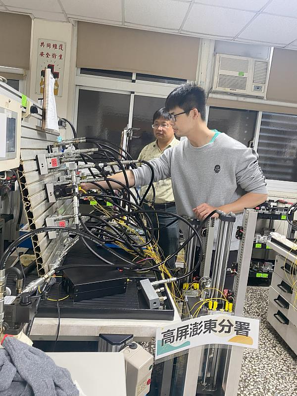 老師指導陳俞成(右一)進行機電控制實務操作。