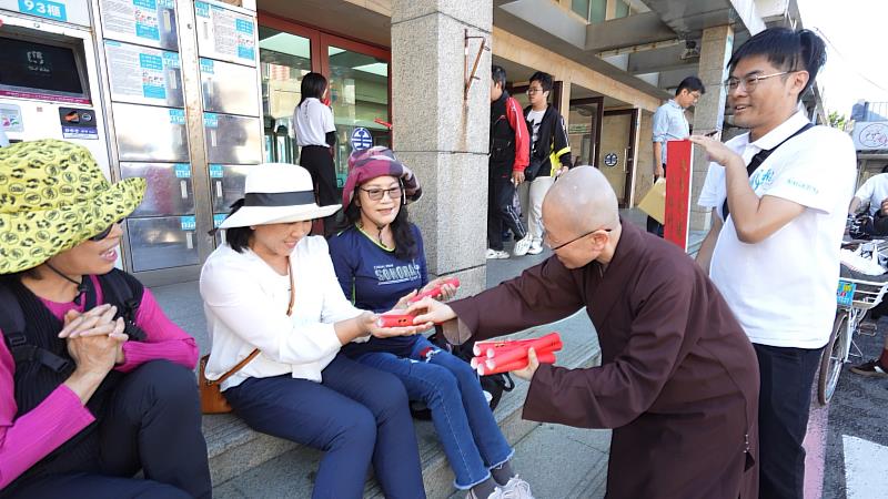 靈鷲山法師在福隆火車站前發春聯給民眾。（圖由靈鷲山佛教教團提供）