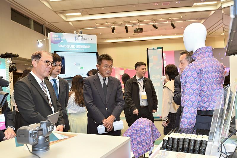 中企署署長李冠志（前排中）參觀由紡織產業綜合研究所開發的「數位布料」技術展示。透過AI模擬真實布料垂墜與光澤感，協助紡織業者將樣品「實轉虛」，設計師可直接線上確認，解決傳統打樣耗時耗材的痛點，加速國際接單效率。