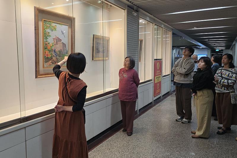 南大飛針繡成果展現場,學員專注聆聽老師解析作品理念,呈現課程中教學與創作交流的學習氛圍。
