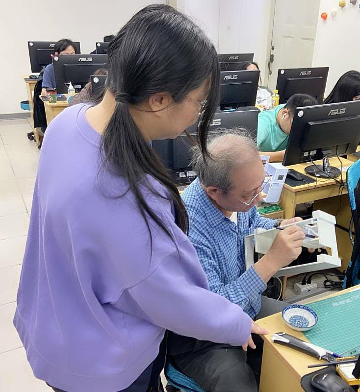 助教在旁協助身障學員（右）製作家具模型。
