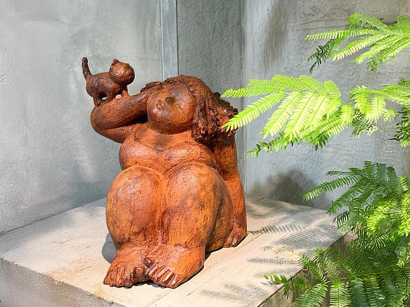 主視覺作品〈貓的呢喃〉中，女性靜靜佇坐，貓輕輕停留其上，如同低聲陪伴的存在。耐候鋼在光影與時間中呈現溫潤鏽色，營造出安靜而親密的觀看氛圍。