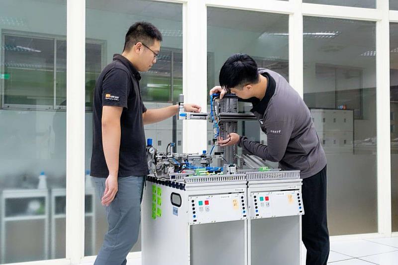 訓練師正在指導學員操作小型自動化產線設備。