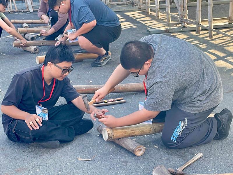 種子學生協助參與者挖鑿竹孔技藝。