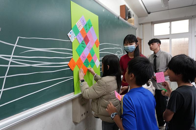 南大聯電課輔中心舉辦聖誕感恩親師生合作手創聖誕樹活動，學童依照老師的指導將祝福卡貼在板上組合成聖誕樹。