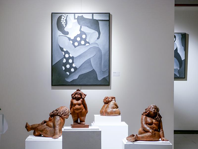 展場作品一景。耐候鋼雕塑與平面作品交織呈現，圓潤厚實的女性形象靜靜佇立於空間中，營造出溫馨而療癒的展覽氛圍，邀請觀眾在其中慢慢感受、靜靜停留。