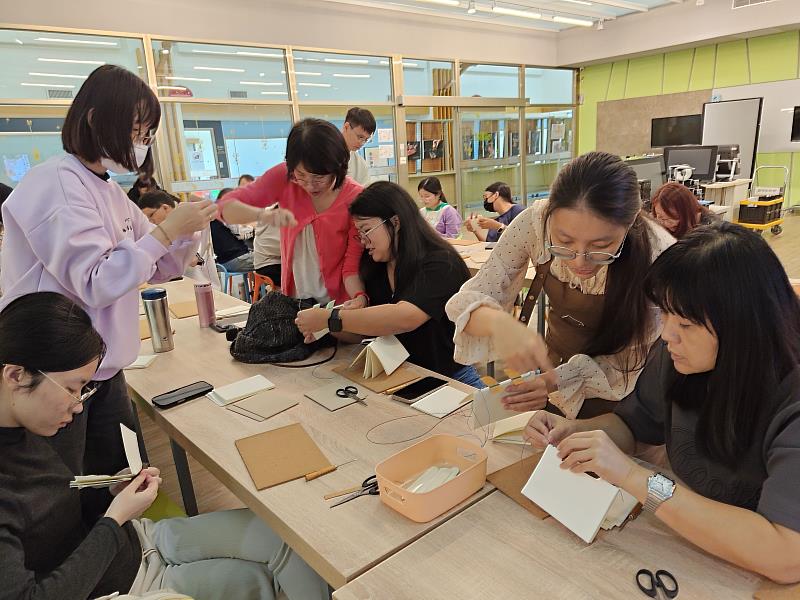 南華大學圖書館舉辦「USR繪本分享會與線裝手工書工作坊」，參加者專注縫製手工書，體驗創作樂趣。