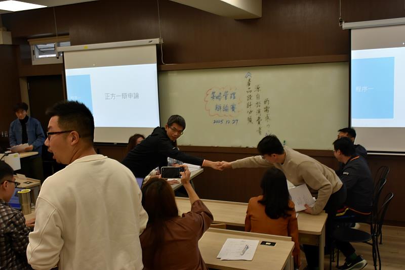 南大管理學院EMBA課堂辯論賽中，正反雙方辯士握手致意，展現專業交流精神。