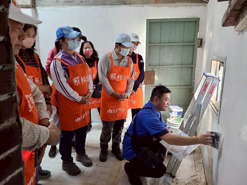 伊甸羅賴把講師教導志工如何粉刷牆壁。