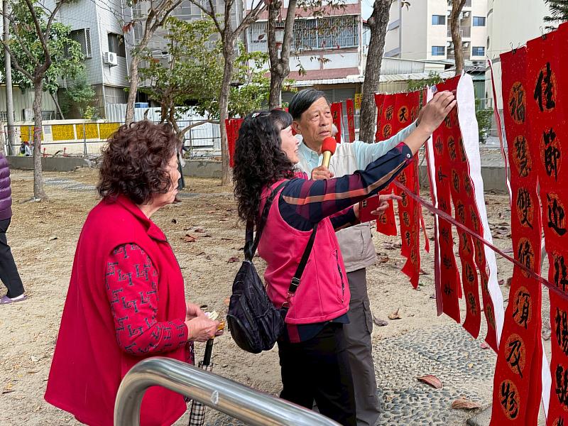 大坑麗澤學會王文瑞理事長帶領軍功社區居民領取手寫春聯。