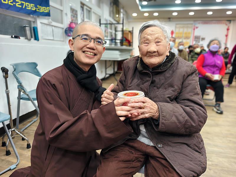 聖山寺大殿香燈賢善法師(左)與致贈平安臘八粥給103歲人瑞。(圖由靈鷲山佛教教團提供)