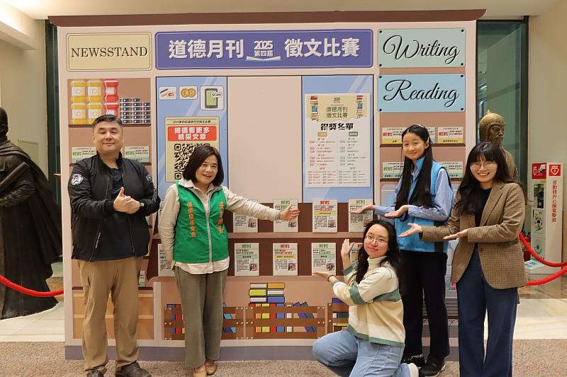 仁愛國中洪桐桐同學在〈深藍色座椅的溫柔〉作品小卡上簽名，與鍾德美執行長（左2）及全班師生分享這份喜悅。