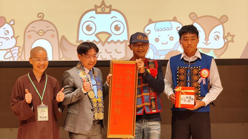 靈鷲山高屏講堂監院法泰法師（左1）致贈心道法師新春墨寶給屏東高樹國中校長盧劍峰（左2）並與入圍全國獎巴同學（右1）合影。（圖由靈鷲山佛教教團提供）