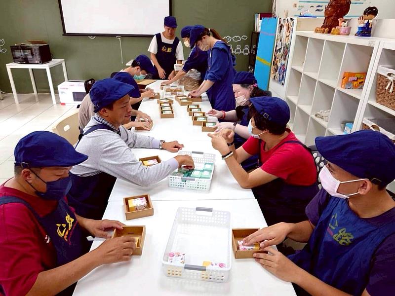 心路工坊青年以流水線分工合作，合力完成「勇氣皂組」包裝，每個人都是不可或缺的一環。圖 / 心路基金會