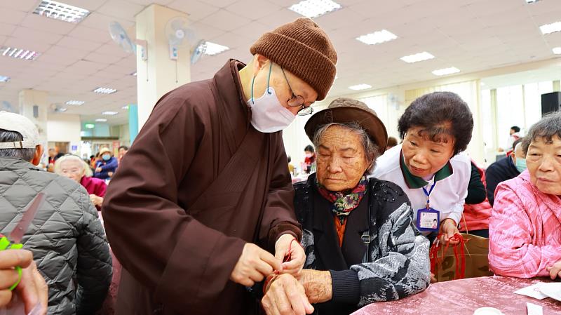 靈鷲山法師為長者們繫上五佛珠，隨身常保平安吉祥。（靈鷲山佛教教團提供）