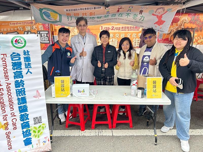 明德里里長感謝社團法人台灣高齡照護暨教育協會（FACES）及南臺科大青銀共創USR團隊的專業照護服務。FACES張家銘理事長（左2）、台南市南區明德里陳瑞華里長（左3）、南臺科大青銀共創USR計畫主持人陳美珠（左4）及USR計畫團隊於救護站前合影。