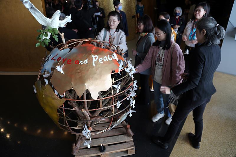 參與「和諧同行、青年朝聖之旅」的代表一一在漂流木地球裝置上掛上和平鴿。（圖由世界宗教博物館提供）