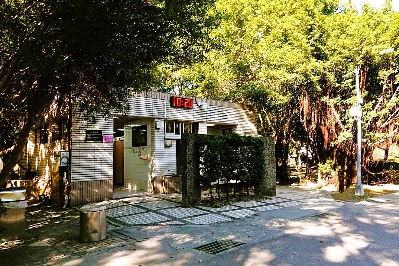 大安森林公園「4號公廁」改建前現況外觀,建物鄰近園路步道,周邊樹蔭環繞。