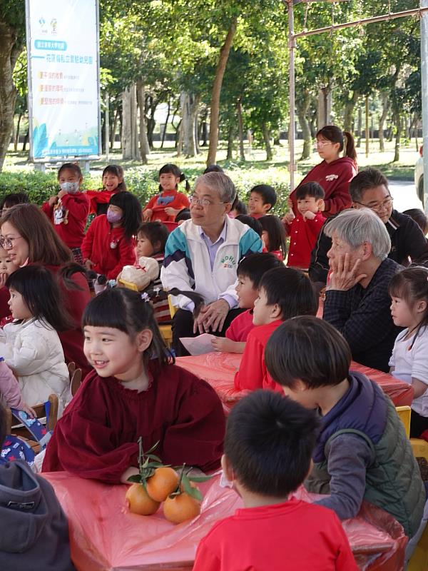 師生圍坐紅桌共享表演時光，紅色桌巾營造辦桌般的熱鬧氣息，現場充滿歡笑與祝福。