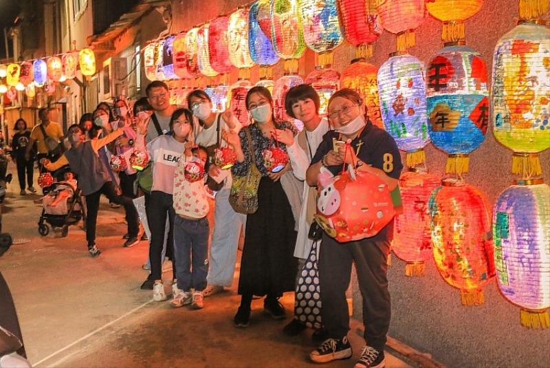 參與提燈夜遊的民眾於神農街港道遺址燈群前大合照，細賞家戶故事花燈，感受老街獨特情懷。