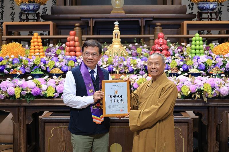 中華郵政公司董事長王國材（左）敬獻郵票紀念框予星雲大師，由都監院慧傳院長代表受領（右）。/中華郵政提供