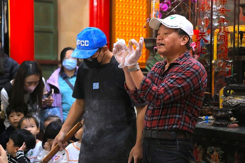 古板蔡師傅向學童展示並講解「已裹上糯米粉的元宵」與「純內餡」的差異。