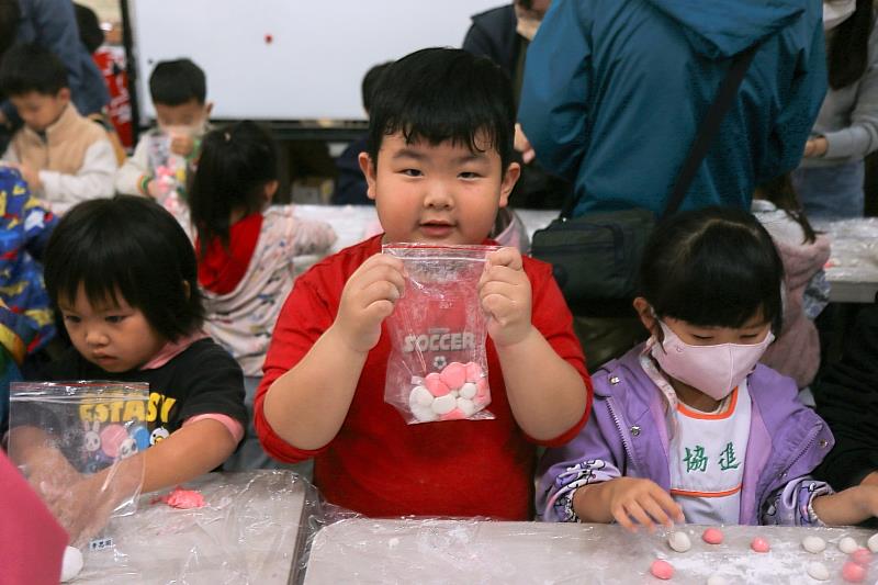 協進幼兒園孩童手捧親自完成的湯圓與蔡師傅教導的元宵，開心展露純真笑容。