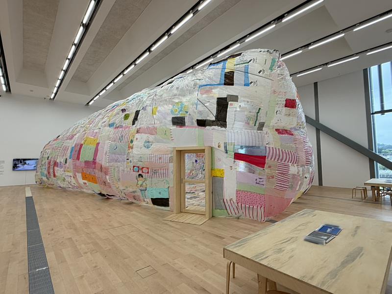 《共織宇宙》展覽呈現「太陽能飛行博物館」大型裝置,以回收塑膠袋拼貼而成,透過太陽熱能升空,實踐無需化石燃料的飛行想像。