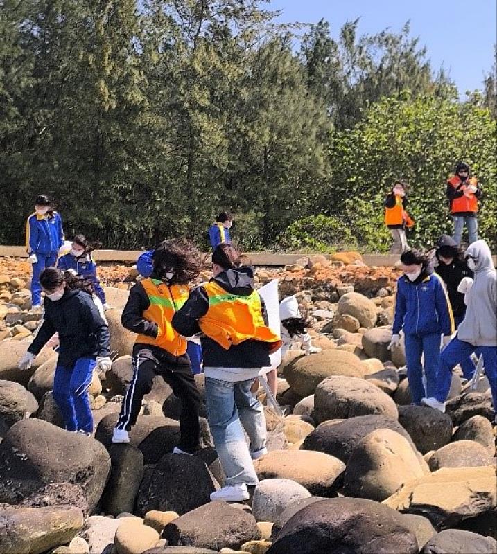 青年们不畏强风，认真净滩。