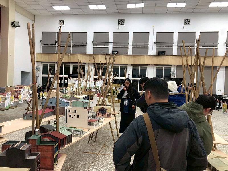遊客在龍崎老街縮尺模型前，聽學生分享龍崎老街建築的故事與地方學習趣事