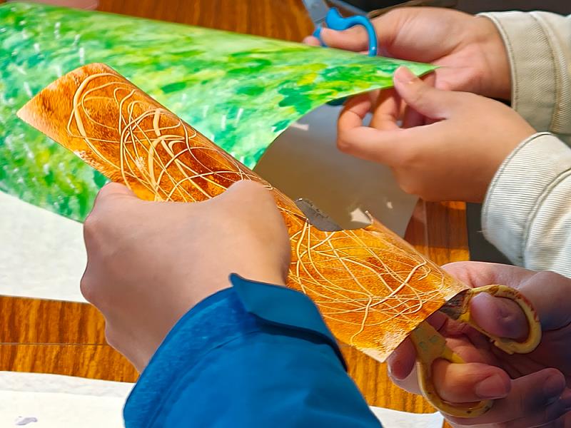 參與者從自行塗鴉的紙張中剪裁形狀，透過色塊組合發展畫面構圖。