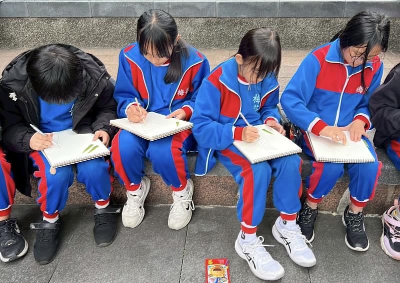 孩子們席地而坐專心作畫，將在展覽中感受到的色彩與想像，一筆一畫呈現在紙上。（圖片為來自新竹縣的梅花國小）