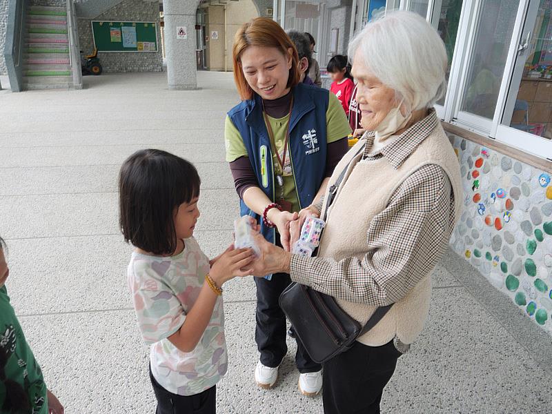 參與老幼共學逾3年的林阿嬤，唱名學童姓名字，發送兒童節禮物。