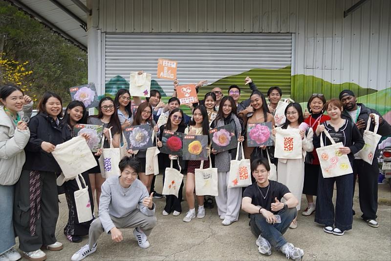 中華大學觀光碩士班學生與菲律賓萊西姆大學Laguna分校交流團在USR茶花場域完成專屬絹印帆布包後開心合影,展現跨文化交流的創意成果。