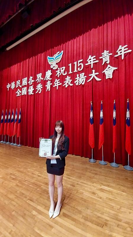 獲頒「全國大專優秀青年」的南臺科大彭芷岳同學，手持當選證書於大會舞台前合影，記錄這份榮耀時刻。