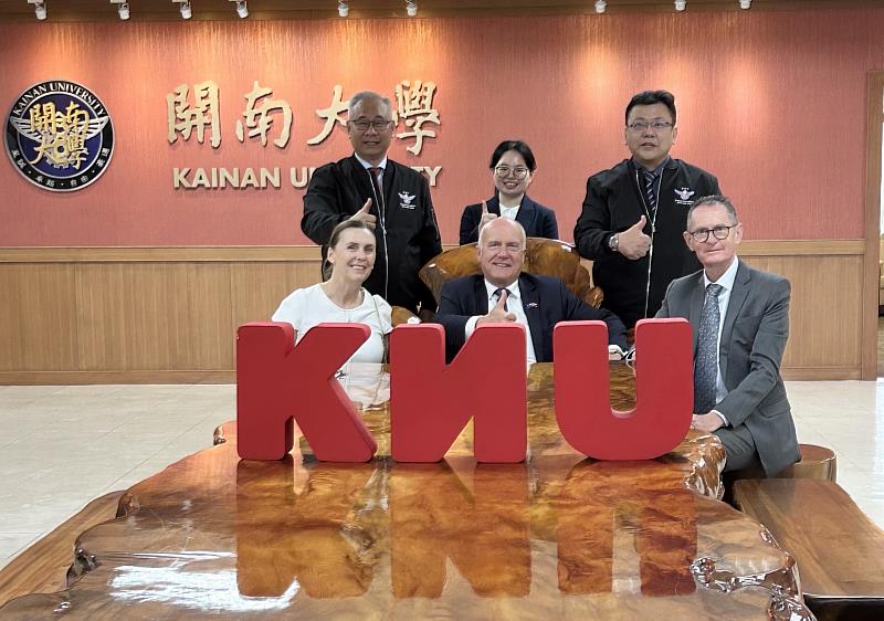 塔斯馬尼亞州財政廳長阿貝茨（中）率團參訪開南大學，與校方代表於KNU標誌前合影，展現友好互動。
