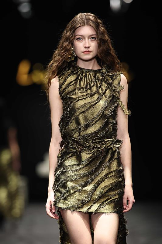 在素材運用上，Liyu Tsai 2026秋冬系列選用法國金色華麗羽毛金蔥布、白色斜紋亮面三醋酸酯，並以輕覆橄欖蕾絲的垂墜下擺延伸柔和層次。（麥羨雲 提供）