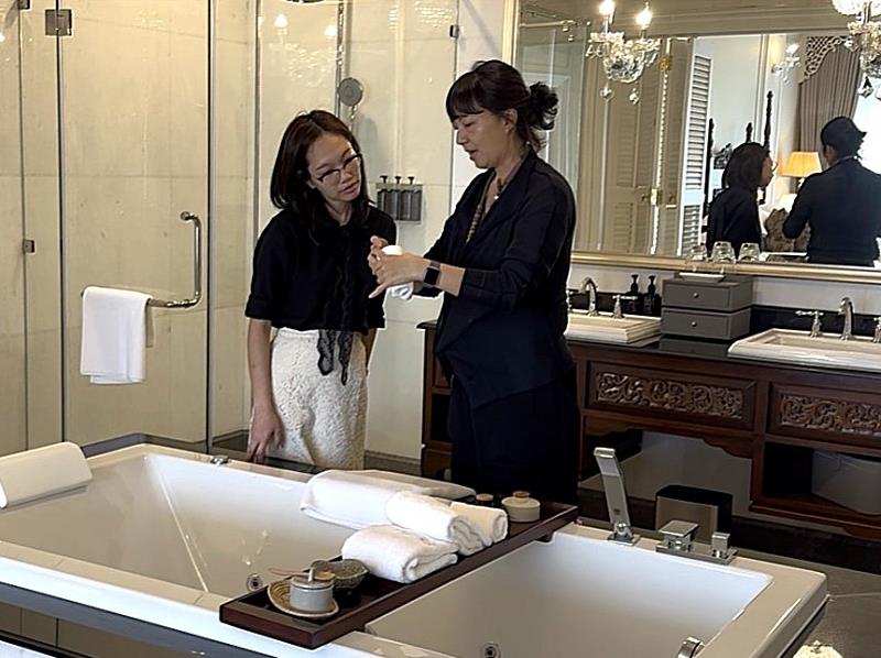 透過情境演練，學生能從細節中掌握高端服務管理的專業內涵。圖為郭心甯老師（右）於總統套房實地指導學生英式管家高端房務管理細節。