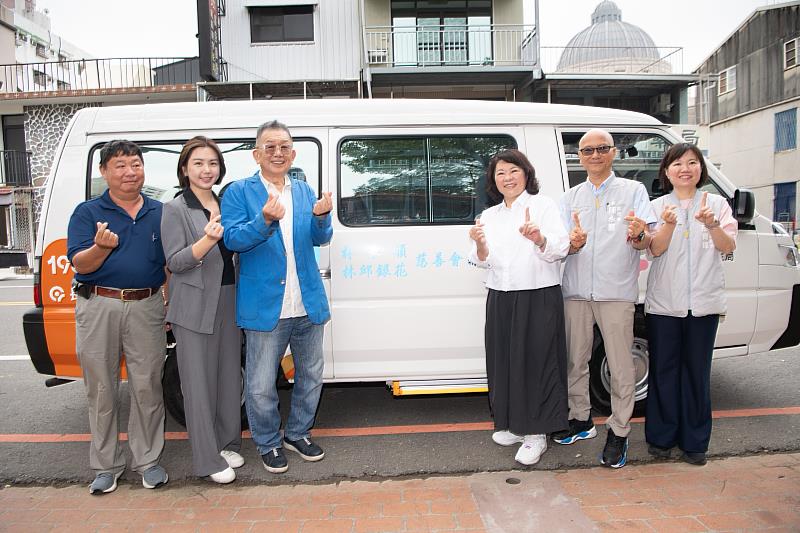 市長與林文村顧問(左3)及市府團隊於長照交通車前合影。
