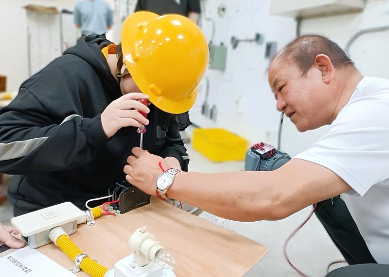 北分署宜蘭職訓場水電職類訓練師陳枝洋（右）指導未就學未就業少年實作簡易電路配線，從手作中產生對技能的興趣。